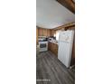 Galley kitchen with white appliances, wood cabinets, and updated flooring at 25 S 102Nd St # 91, Mesa, AZ 85208