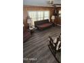 View of a cozy living room with wood paneling, patterned flooring, lamps, and a ceiling fan at 25 S 102Nd St # 91, Mesa, AZ 85208