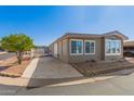 Tan home featuring a long driveway, a citrus tree, and decorative rock landscaping at 5735 E Mcdowell E Rd # 213, Mesa, AZ 85215