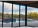 View of the pool and desert landscape through large glass doors, blending indoor and outdoor living at 10354 E Celestial Dr, Scottsdale, AZ 85262