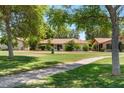 Charming single-story home with a tile roof, surrounded by lush greenery and a well-manicured lawn at 1202 Leisure World --, Mesa, AZ 85206
