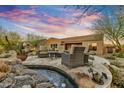 Desert home backyard with a cozy seating area near a rock waterfall feature and view of the beautiful Arizona sunset at 37170 N Greythorn Cir, Carefree, AZ 85377