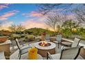 Desert home backyard with a stone firepit and chairs, complemented by desert landscaping and views of the Arizona mountains at 37170 N Greythorn Cir, Carefree, AZ 85377