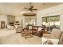 Spacious living room featuring a ceiling fan, plush seating, stone fireplace and bright natural light at 3822 E Tracker Trl, Phoenix, AZ 85050