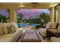Comfortable covered patio with plush seating, a view of the pool, and a vibrant sunset at 7380 E Turquoise Ave, Scottsdale, AZ 85258