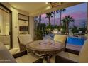 Inviting outdoor patio with a dining set, fireplace, and sparkling pool at dusk at 7380 E Turquoise Ave, Scottsdale, AZ 85258