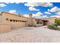 Inviting desert home featuring neutral stucco, a tile roof, a two-car garage, and beautiful stone driveway and walkway at 8003 E Sands Dr, Scottsdale, AZ 85255
