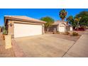 View of the home's two car garage and driveway with neat landscaping and nearby houses at 11226 W Glenrosa Ave, Phoenix, AZ 85037