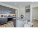 Modern kitchen features gray cabinets, stainless steel appliances, and a granite island with seating at 17966 W Long Lake Rd, Goodyear, AZ 85338