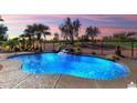 Beautiful backyard pool with rocks and a small waterfall, next to a golf course at 23024 N De La Guerra Ct, Sun City West, AZ 85375