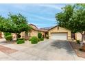 Inviting single-story home with a two-car garage, desert landscaping, and a well-kept front yard with mature trees at 10414 W Windsor Ave, Avondale, AZ 85392