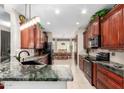 Well-appointed kitchen with granite countertops, black appliances, and dark wood cabinetry at 18867 N Cactus Flower Way, Surprise, AZ 85387