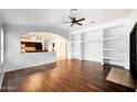 Bright living room featuring hardwood floors, ceiling fan, and built-in shelving for stylish decor at 20838 N 39Th Dr, Glendale, AZ 85308