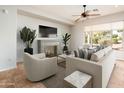 Comfortable living room with fireplace, neutral furniture, ceiling fan, and lots of natural light at 22236 N Arrellaga Dr, Sun City West, AZ 85375