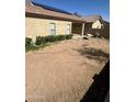 View of the backyard with dirt landscaping, a covered patio, and a light-colored house with solar panels at 28202 N Willemite Dr, San Tan Valley, AZ 85143