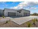 Modern home with a spacious driveway leading to multiple garage doors and desert landscaping at 36004 N Prickley Pear Rd, Cave Creek, AZ 85331