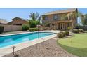 Backyard features a large pool, putting green, outdoor kitchen, and patio perfect for entertaining at 44390 W Buckhorn Trl, Maricopa, AZ 85138