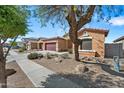 A desert home featuring low-maintenance landscaping, a driveway, and nearby mature tree at 5318 W Grenadine Rd, Laveen, AZ 85339
