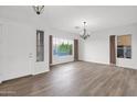 Bright living room with elegant chandeliers, large windows, neutral walls, and wood-look floors, ready for personalization and comfort at 6793 W Angela Dr, Glendale, AZ 85308