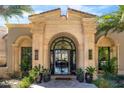 Grand entrance features a decorative iron door, stone columns, and lush plants, inviting guests into a luxurious home at 7046 N 59Th Pl, Paradise Valley, AZ 85253