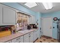 Bright kitchen with white cabinetry, neutral countertops, and double basin sink at 11012 W Caron Dr, Sun City, AZ 85351
