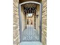 Wrought iron security gate offers a glimpse of the home's entry, framed by elegant stone pillars at 19571 E Strawberry Dr, Queen Creek, AZ 85142