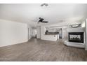 Open-concept living area with wood-look tile, fireplace, and an adjoining kitchen at 26066 N 72Nd Ave, Peoria, AZ 85383