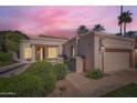 Charming single-story home featuring a two-car garage, desert landscaping, and secure gated entry at sunset at 10062 E Cinnabar Ave, Scottsdale, AZ 85258