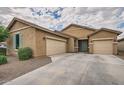 Stylish single-story home with tan stucco, a tile roof and large driveway and two-car garage at 10528 W Crown King Rd, Tolleson, AZ 85353