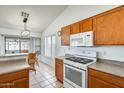 Bright kitchen featuring wooden cabinetry, white appliances, tile flooring, and breakfast nook at 16034 W Carmen Dr, Surprise, AZ 85374