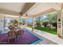 Inviting covered patio with comfortable seating and a view of the landscaped backyard and fountain at 16769 W Brookhaven Ct, Surprise, AZ 85387