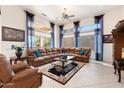 Bright living room with large windows, tile floors, and a comfortable leather sectional sofa at 16769 W Brookhaven Ct, Surprise, AZ 85387