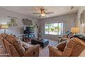 Cozy living room with a ceiling fan, plush seating, and a large window offering natural light at 19615 N Sunburst Way, Surprise, AZ 85374