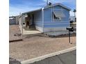 Cozy blue mobile home with awning, covered porch and desert landscaping at 2121 N Center St # 141, Mesa, AZ 85201