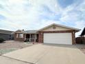 Suburban brick home boasts a wide driveway leading to an attached two-car garage, offering ample parking at 8217 E Medina Ave, Mesa, AZ 85209