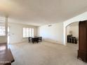 Bright living room featuring neutral carpet, arched entryway and a window with plantation shutters at 8217 E Medina Ave, Mesa, AZ 85209