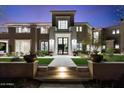 Elegant home featuring a beautifully landscaped front yard, a symmetrical facade, and inviting entryway with uplighting at 9735 E Kemper Way, Scottsdale, AZ 85255