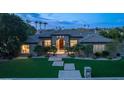 An attractive home at dusk, with landscape lighting and lush front yard at 7150 E Balfour Rd, Paradise Valley, AZ 85253