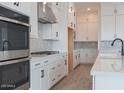 Close-up of a modern kitchen with white cabinets, stainless steel appliances, and black hardware at 1246 E Penedes Dr, Gilbert, AZ 85298