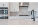 Contemporary kitchen featuring stainless steel appliances, black faucet, and gray geometric backsplash at 1246 E Penedes Dr, Gilbert, AZ 85298
