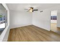 Well-lit empty room featuring wood-look floors, a ceiling fan, neutral walls and large windows at 2224 E Glade Ave, Mesa, AZ 85204