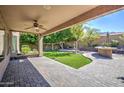 Inviting covered patio with brick flooring overlooks a landscaped backyard with a built-in grill and green lawn at 2609 W Mcneil St, Phoenix, AZ 85041