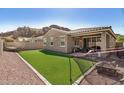 Home's backyard with low-maintenance synthetic grass, paver accents, covered patio, and mountain views at 10454 W Maya Way, Peoria, AZ 85383