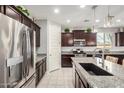 Well-equipped kitchen featuring stainless steel appliances, granite countertops, dark wood cabinets, and large island at 10454 W Maya Way, Peoria, AZ 85383