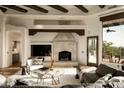 Cozy living room featuring a stone fireplace, beamed ceilings, and comfortable seating with an outdoor view at 10596 E Yearling Dr, Scottsdale, AZ 85255