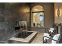 Close up of outdoor water feature with black rock and stone design under an arch window, adjacent to seating area at 11320 N Crestview Dr, Fountain Hills, AZ 85268