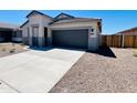 Single-story house shows a modern elevation, smooth concrete driveway, well-kept desert landscape, and a two-car garage at 11959 E Aster Ln, Florence, AZ 85132