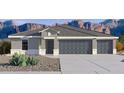 Charming home featuring a three-car garage, neutral paint, and desert landscaping with mountains in the background at 12456 E Bahia Ct, Florence, AZ 85132