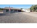 Single-story brick home with an American flag, a long driveway, and a low-maintenance rock yard at 6029 W Pershing Ave, Glendale, AZ 85304