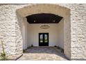 Grand entrance featuring stone archway, black double doors, and decorative chandelier at 7528 E Windrose Dr, Scottsdale, AZ 85260